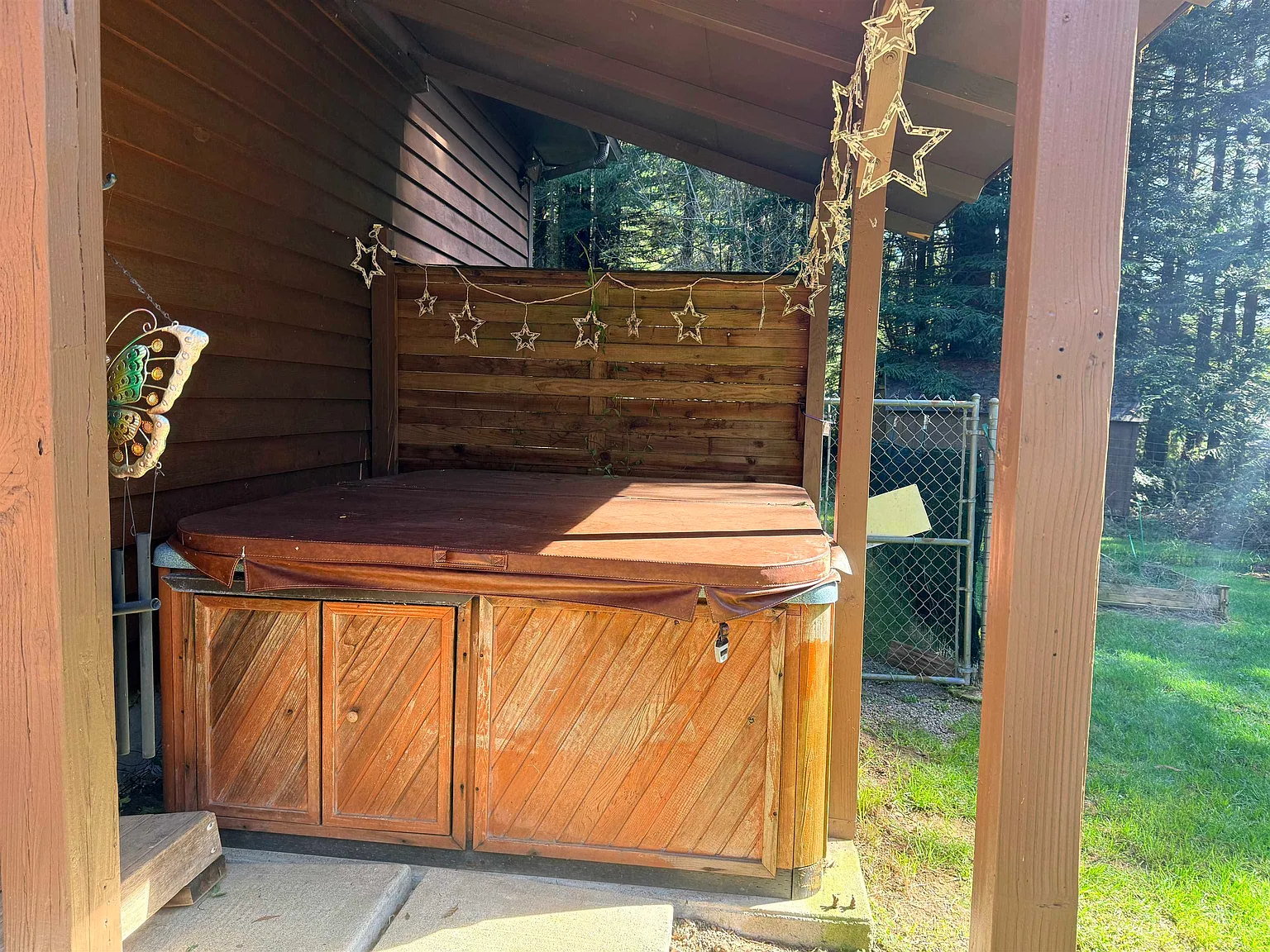 Hot tub on a covered wood platform beside the house.